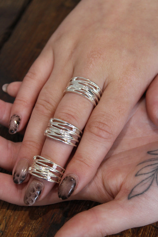 A wide silver ring composed of multiple interlocking bands, accented with small round gemstones, silver and cubic zirconia